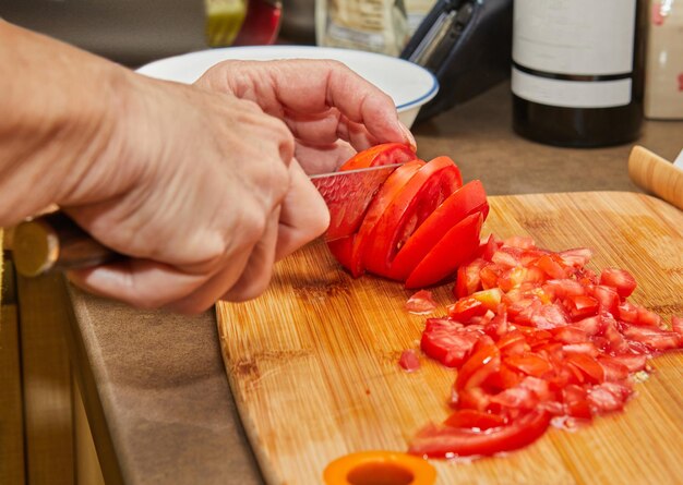 Woman cuts tomatoes for cooking at home using recipe from the internet