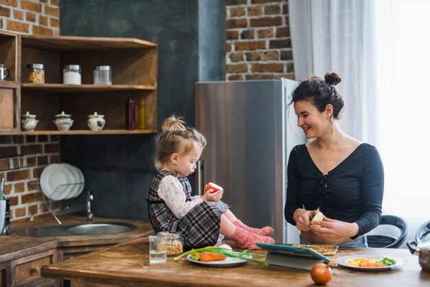 Woman cutting apples near daughter