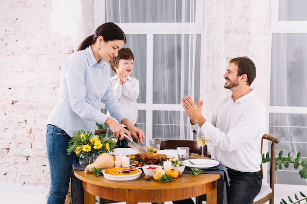 Woman cutting baked chicken at table