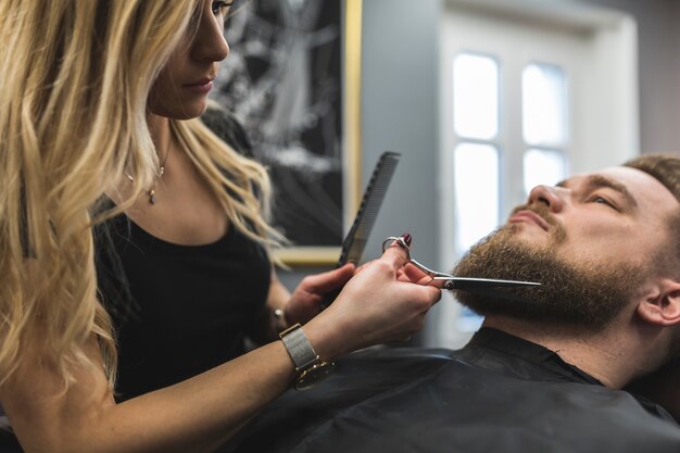 Woman cutting beard of man
