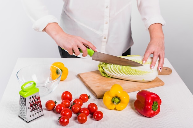 Woman cutting cabbage on wooden board