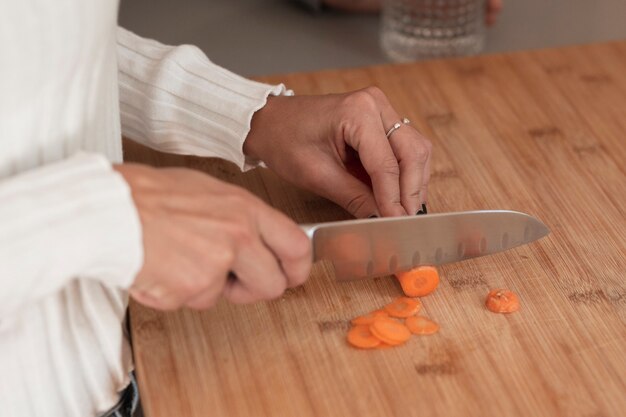Женщина режет морковь крупным планом