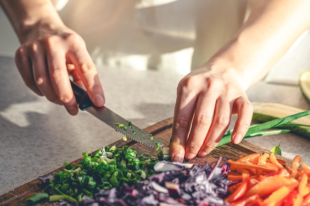 Foto gratuita donna che taglia e trita la cipolla con il coltello sulla tavola di legno