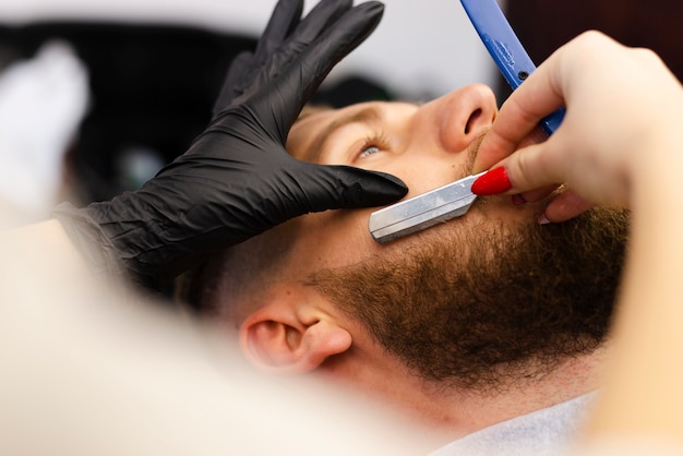 Woman cutting a client's beard close-up