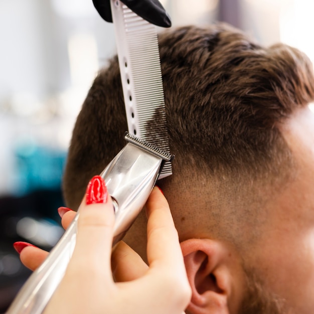 Foto gratuita donna che taglia il primo piano dei capelli del suo cliente