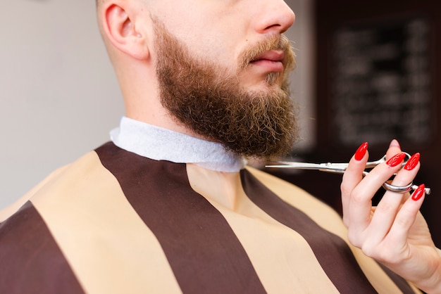 Woman cutting a man's beard at a professional barber shop