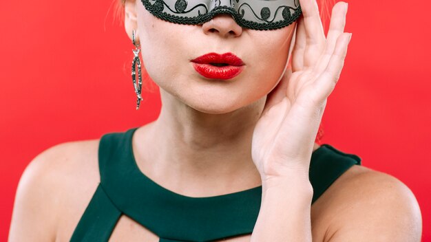 Woman in dark carnival mask blowing kiss