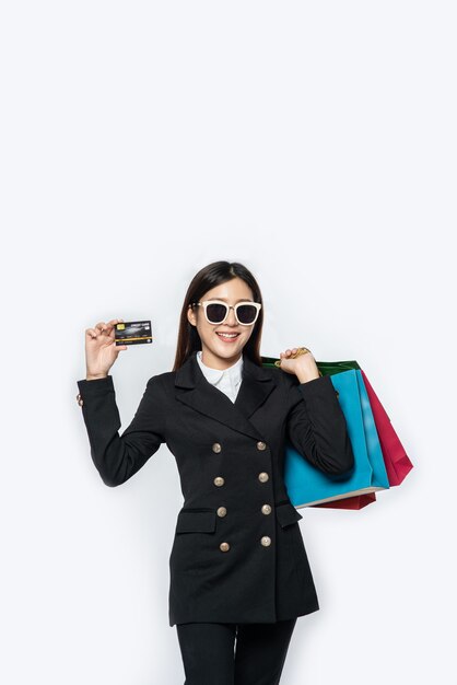 Woman in dark wear glasses, go shopping, carries credit cards, and lots of bags
