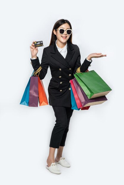 暗い眼鏡をかけている女性、買い物に行く、クレジットカードを運ぶ、そしてたくさんのバッグ