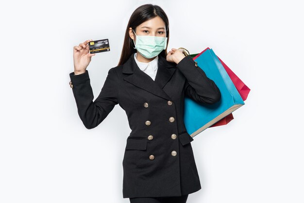 Free photo a woman in dark and wearing a mask walks shopping, carries credit cards, and lots of bags