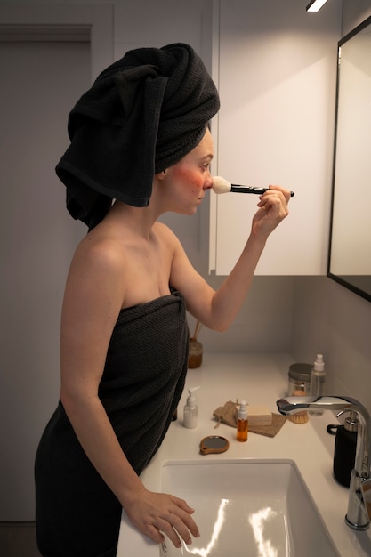 Женщина, страдающая розацеа, наносит макияж кистью