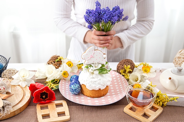 A woman decorates a table with plowing treats with flowers. Easter holiday concept.