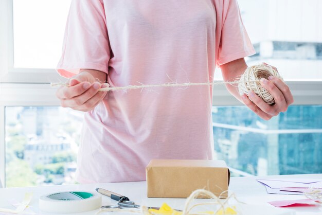 Woman decorating the box with thread on table