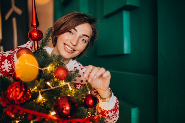 Woman decorating christmas tree with red balls
