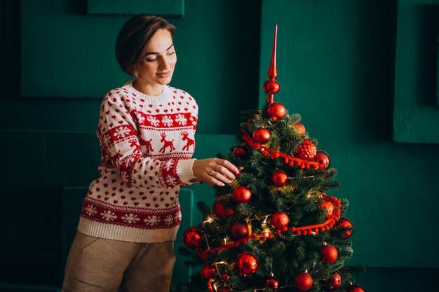 赤いおもちゃでクリスマスツリーを飾る女性