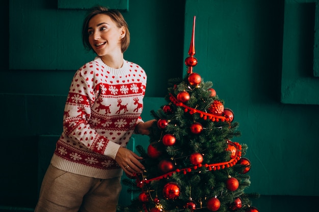 Woman decorating christmas tree with red toys