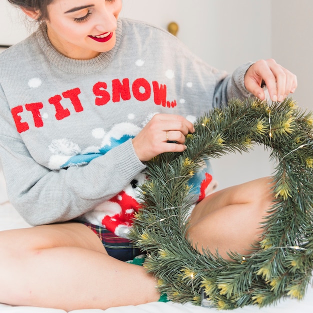 Woman decorating Christmas wreath with garland 