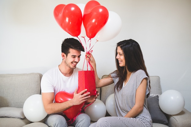 Женщина доставки ее бойфренд воздушных шаров и красный мешок