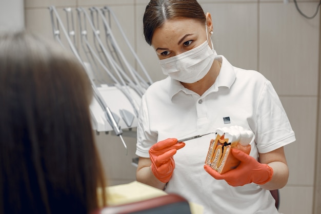Женщина в стоматологическом кресле. Стоматолог учит правильному уходу. Красавица лечит зубы