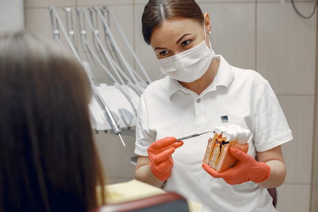 歯科用椅子の女性。歯科医が適切なケアを教えます。美容は彼女の歯を扱います