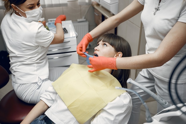 歯科用椅子の女性。女の子は歯科医によって検査されます。歯科医は女の子の歯を扱います