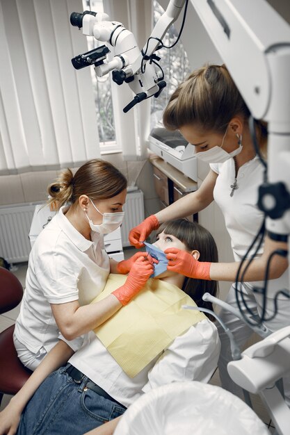 歯科用椅子の女性。女の子は歯科医によって検査されます。歯科医は女の子の歯を扱います