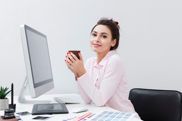 Woman at desk enjoying a cup of coffee