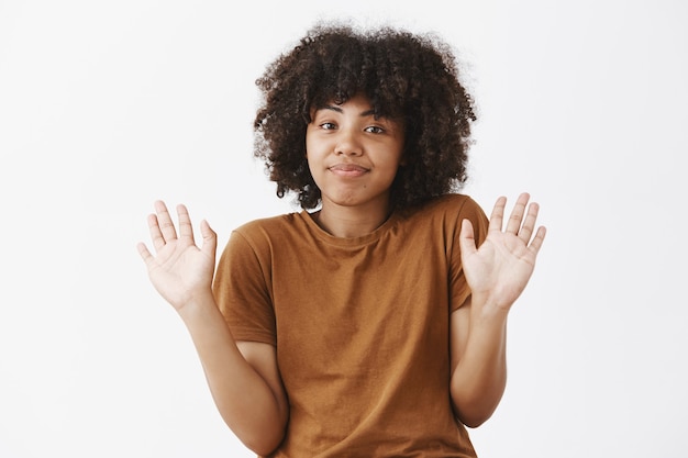 Woman deying her resonsibility raising hands in surrender and smiling with sorry look being uninvolved and unaware of what happening standing careless and indifferent