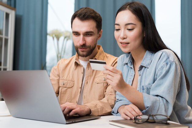 Woman dictating credit card information to man on laptop