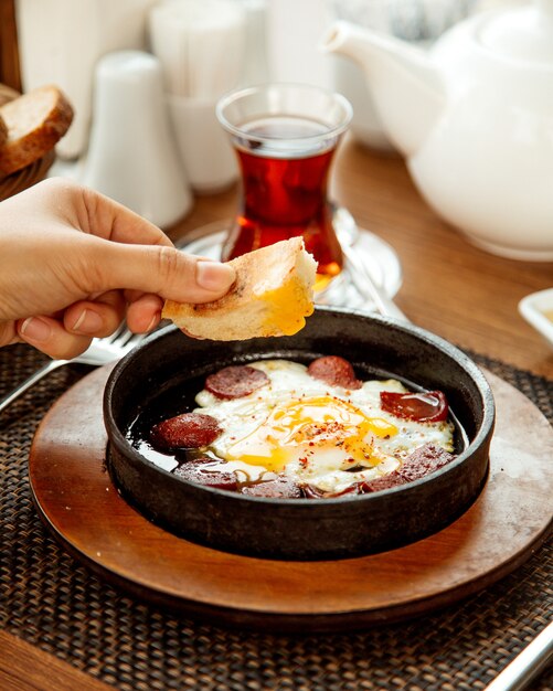 Woman dipping bread into egg and sausage dish