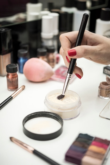 Woman dipping brush in beauty product