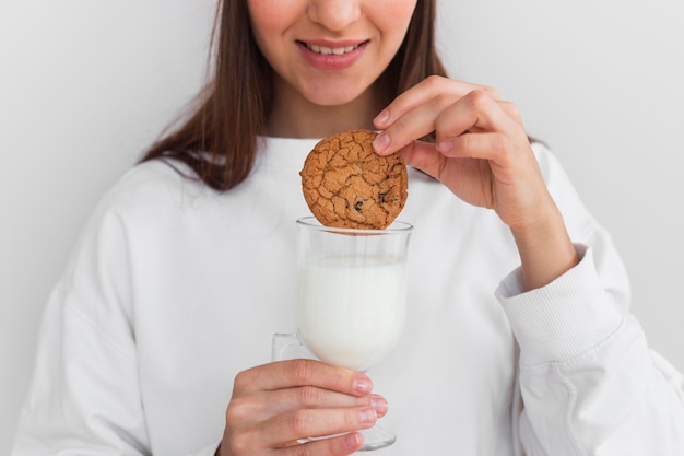 Free photo woman dipping cookie in milk