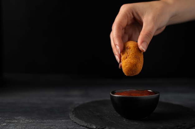 Woman dipping a croquette in ketchup