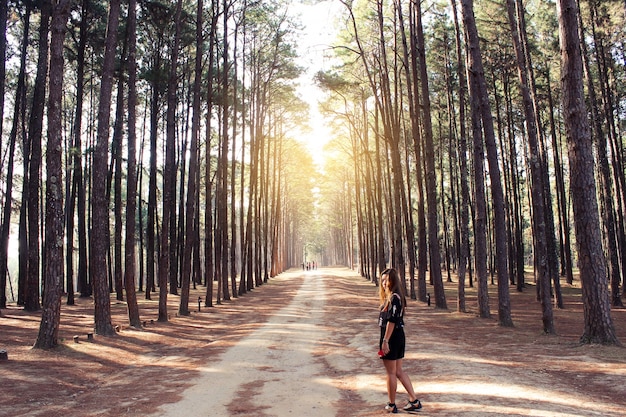 Foto gratuita donna su una strada sterrata con alberi ai lati