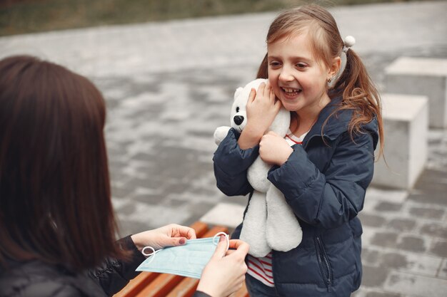 Woman in a disposable mask is teaching her child to wear a respirator