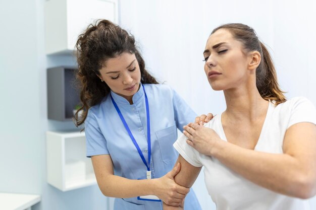 Женщина-врач-остеопат в медицинской форме фиксирует плечевые и спинные суставы пациентки в клинике мануальной терапии во время визита Профессиональный остеопат во время работы с концепцией пациента