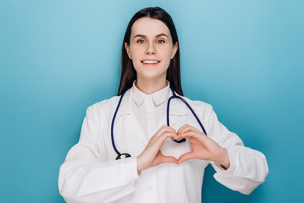 Женщина-врач показывает жест сердца и улыбается