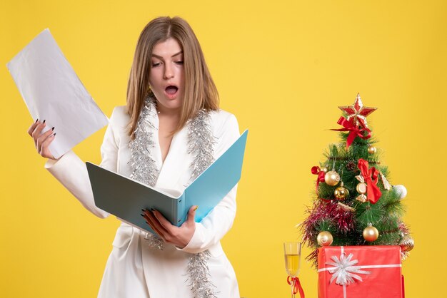 woman doctor standing holding documents on yellow