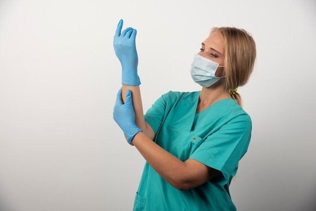 Free photo woman doctor wearing latex gloves and medical mask.