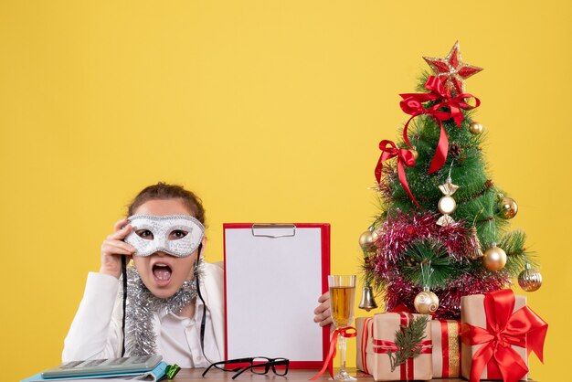 woman doctor wearing party mask and file note on yellow