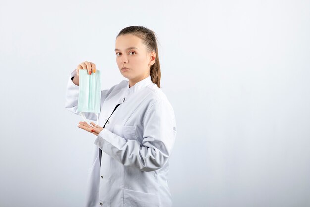 Woman doctor in white uniform showing a medical mask 