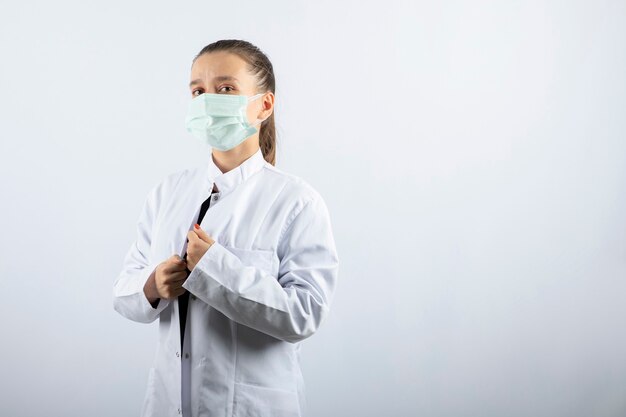 Женщина-врач в белой форме в медицинской маске