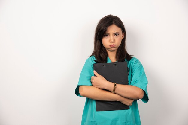 Woman doctor with clipboard holding her breath on white background.