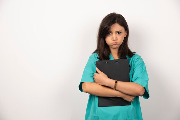 Woman doctor with clipboard holding her breath on white background.