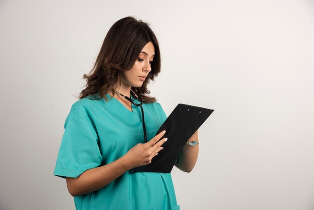 Woman doctor with stethoscope carefully reading the papers.