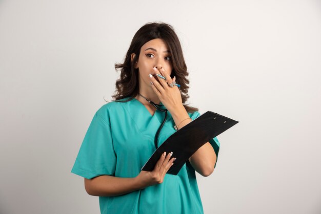 Woman doctor with stethoscope surprised after reading the papers.