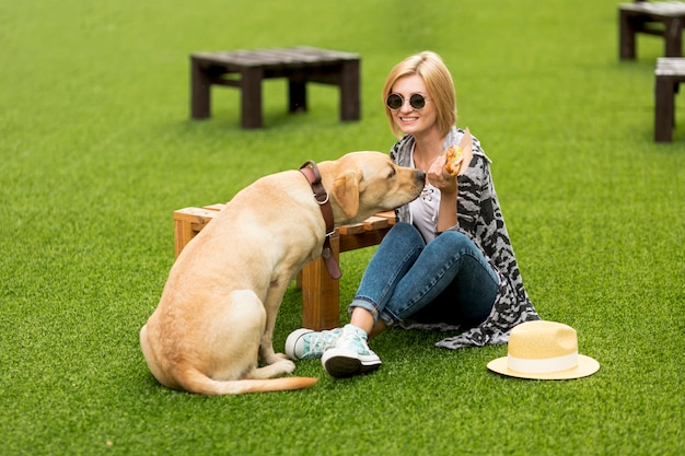 Woman and dog eating food in park