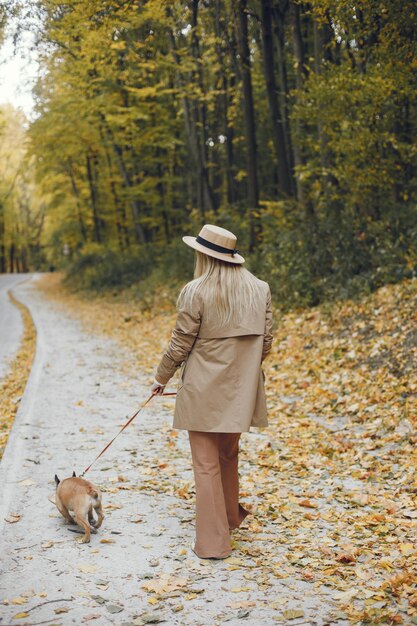 秋の公園で女性と犬が遊んで楽しんでいます
