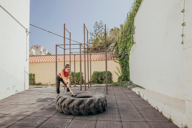 Woman doing crossfit with hammer and wheel