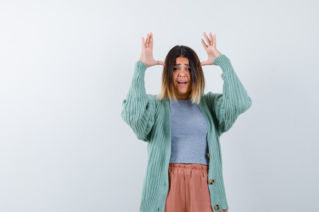 Woman doing ears gesture in casual clothes and looking anxious. front view.